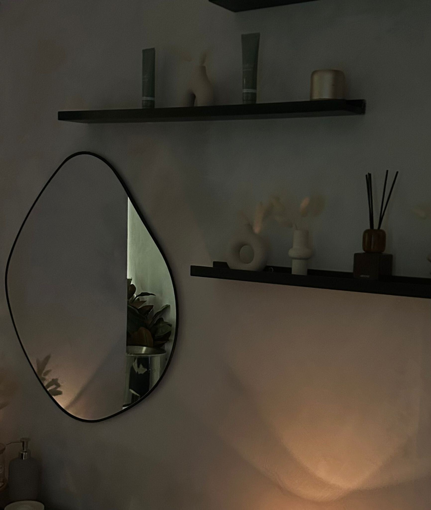 The calm, candle-lit studio — soft lighting, a sculptural mirror and natural skincare on the shelves.
